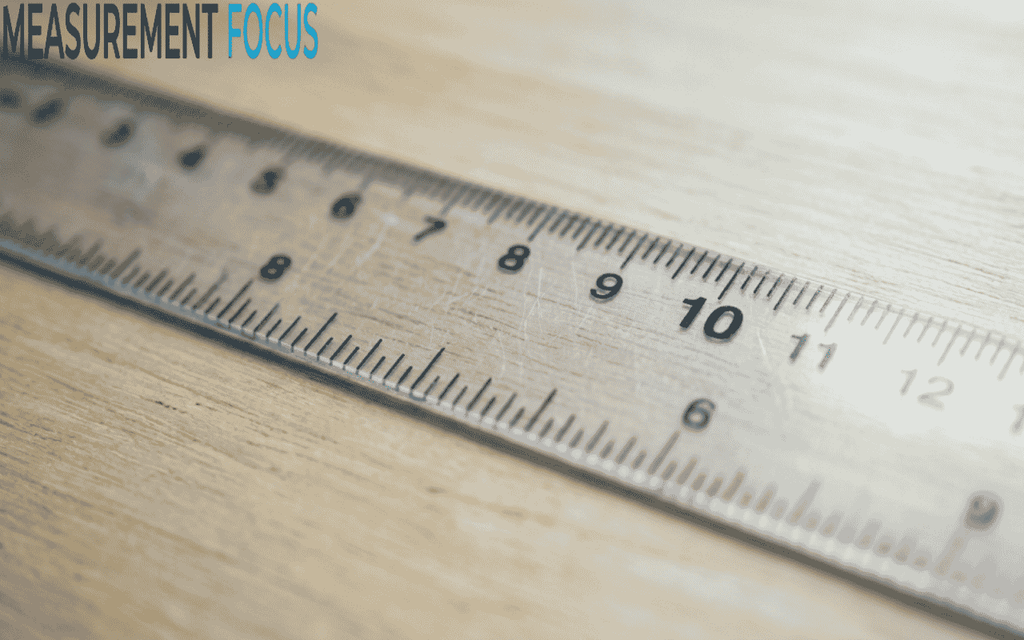 Close up of a clear ruler on a light wood surface, focused on the 10 inches mark